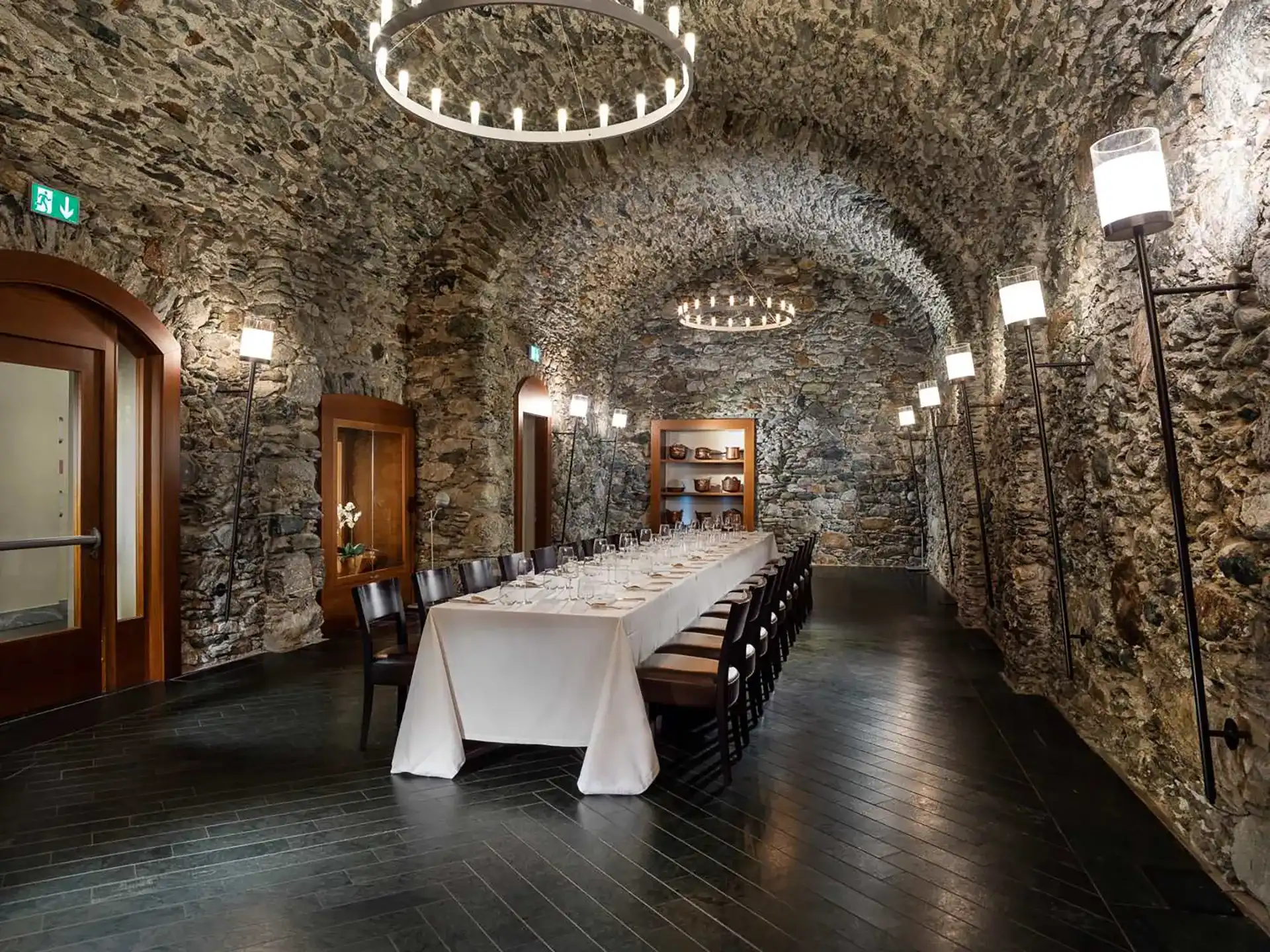 Nell'immagine, la Sala Meeting Medievale del Grand Hotel della Posta: al centro della sala c'è una lunga tavola apparecchiata. Sul soffitto, delle volte in pietra da cui pendono due lampadari.