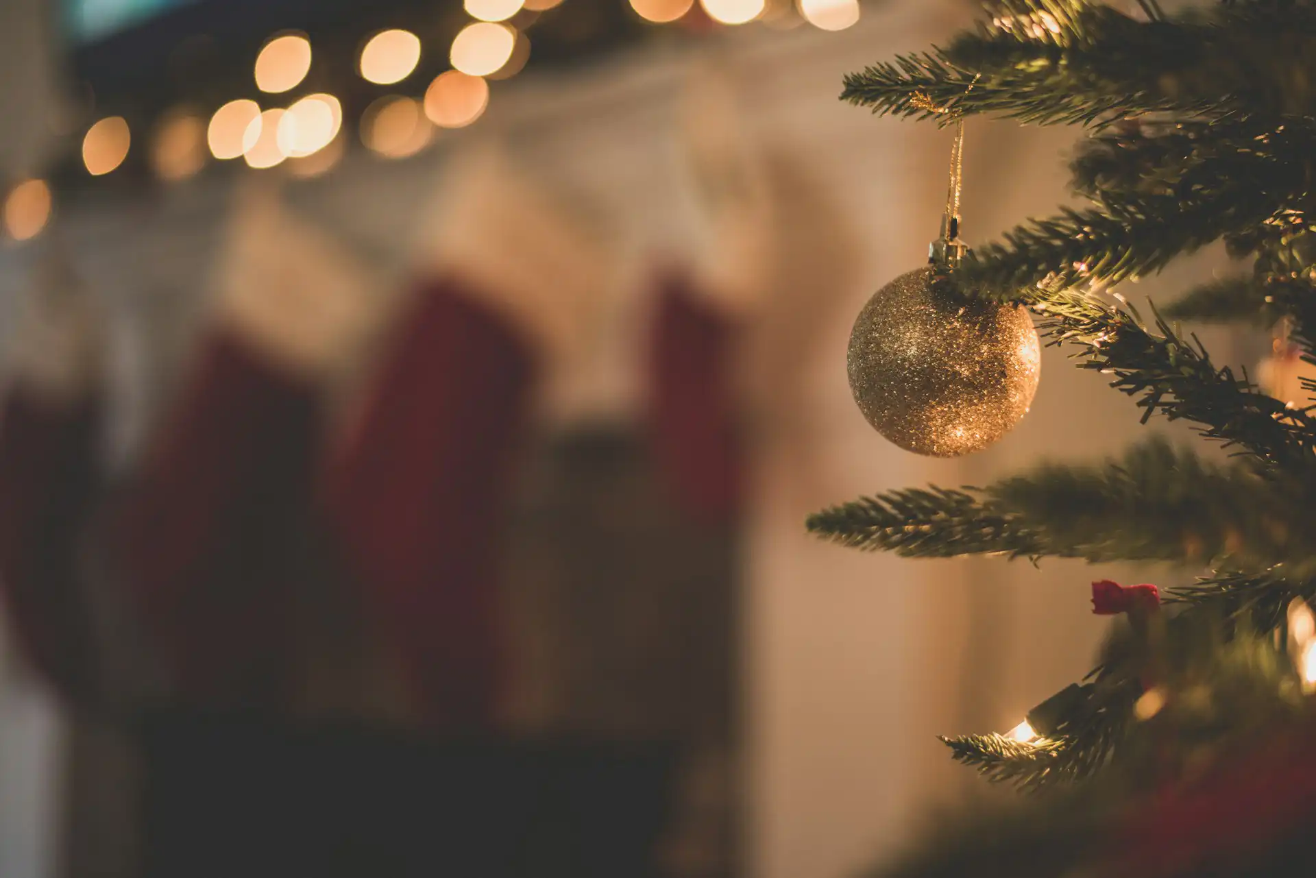 Nell'immagine, il primo piano di una pallina dorata appesa ad un albero di Natale.